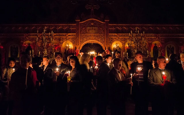 Parishioners holding candles after the ending of an evening Easter Mass in an Orthodox church.