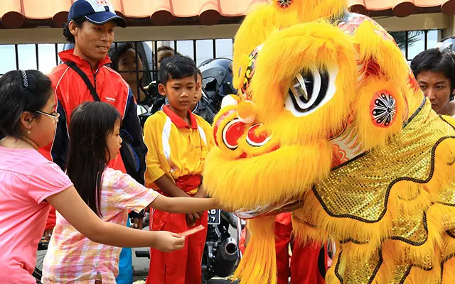 Children with parents meet the lion at a Chinese New Year parade.