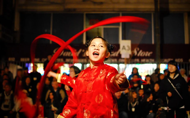 A young girl dressed in traditional red clothes takes part in a Chinese New Year parade.