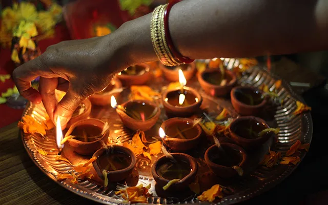 A woman lights up the diyas (oil lamps) an incremental part of the Diwali celebration.