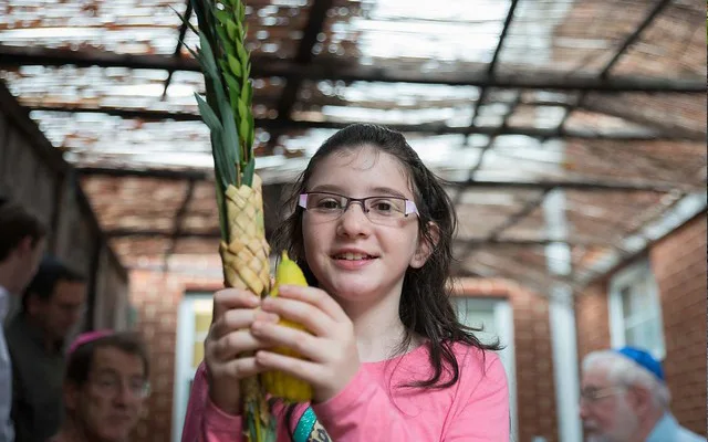 A little girl holding the elements of the four species ceremony (etrog and lulav).