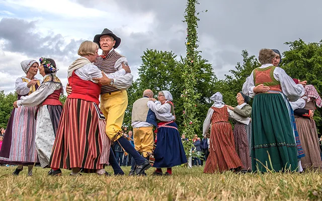 Folk dances with pair on traditional clothes around the Midsommar pole in Vaxholm, Stockholm