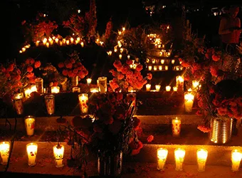 Lit candles decorating a gravesite during the night.