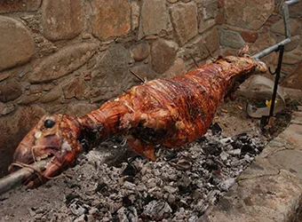 A whole spit lamb roasting over the fire.