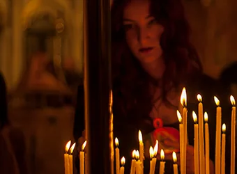 A woman lights up a candle in a church.