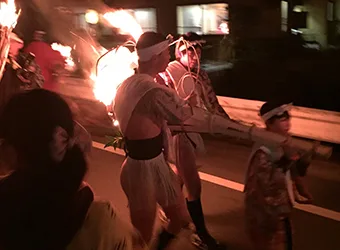 A child & teenagers carrying a big fire torch.