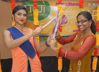 Two women holding sticks dancing Dandiya.