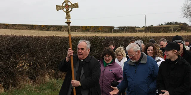 A priest with a cross leads a religious procession commemorating St. Patrick's Day in Downpatrick.