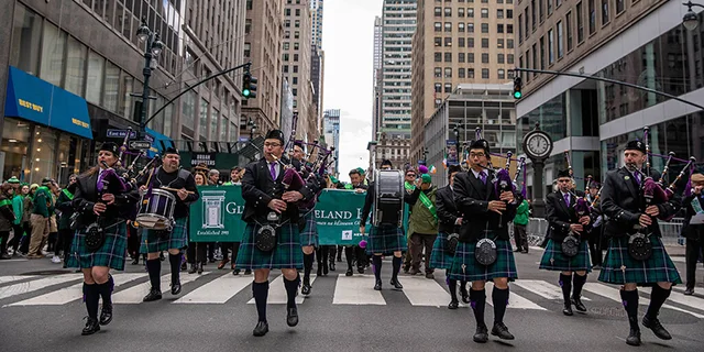 Marching band in traditional Irish outfit parading in New York streets.