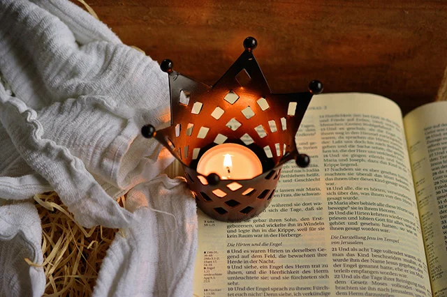 Hay, lit candle, and a bible indicating the narrative of Epiphany.