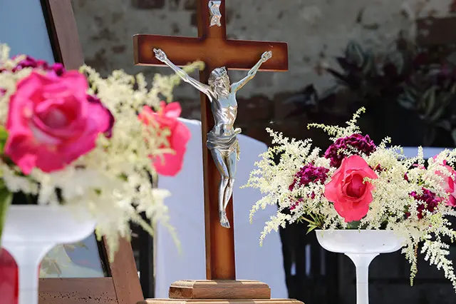 A statue of crucifixes showing Jesus on the cross surrounded by flowers as part of the procession of Corpus Christi.