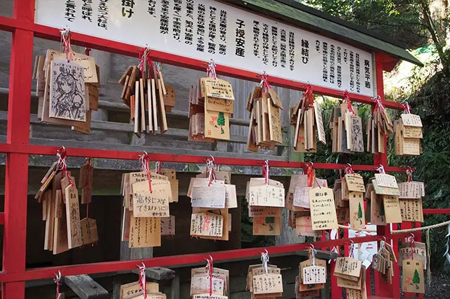 Small wooden plaques with prayers and wishes written on them (Ema) hanging at Shinto Shrine.