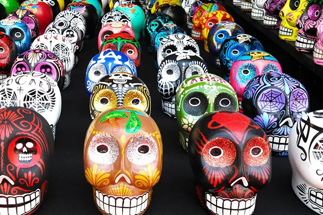 Colorful wooden skulls (calaveras) of the Day of the Dead lying on a table.