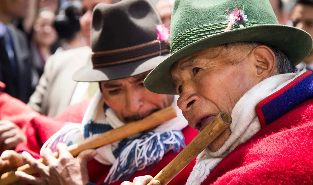 Two men with indigenous origin are playing the flute during Inti Raymi celebrations.