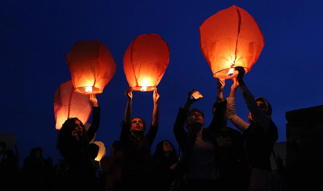 People releasing red wish-lanterns to the night sky. A typical tradition of the Lantern Festival.