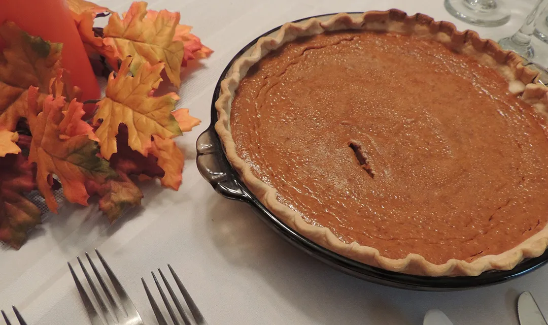 A pumpkin pie on a set Thanksgiving table.