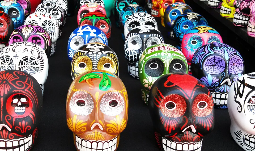 Colorful wooden skulls (calaveras) of the Day of the Dead lying on a table.